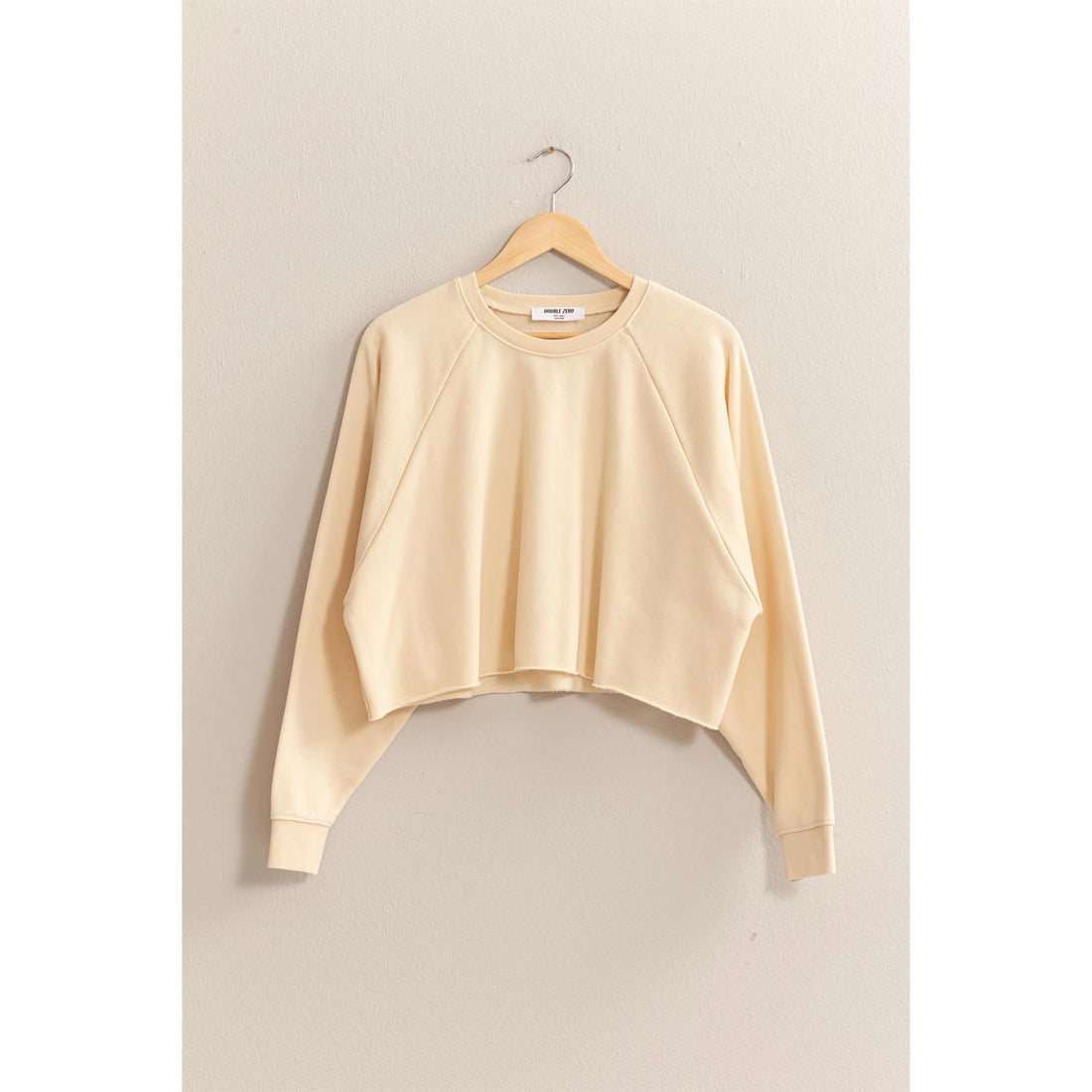 Beige sweatshirt on a hanger against a beige background