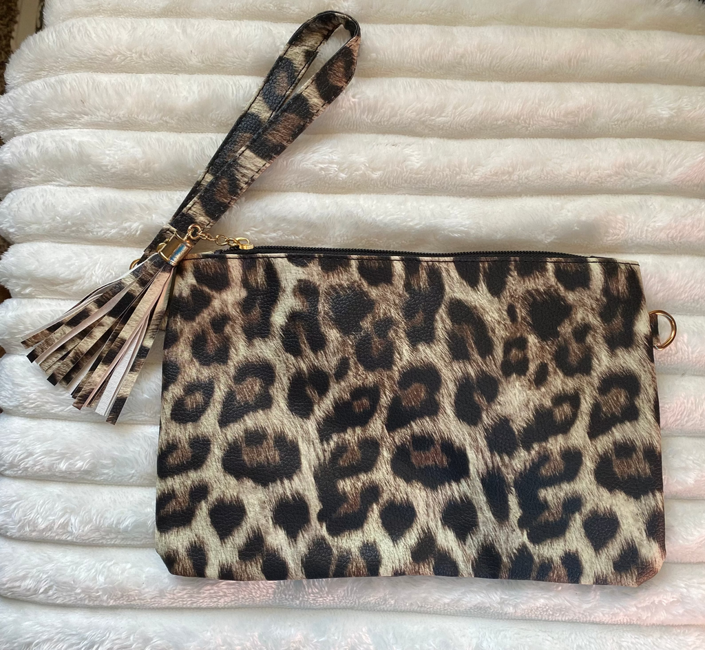 Leopard print clutch with matching wristlet on a textured white surface