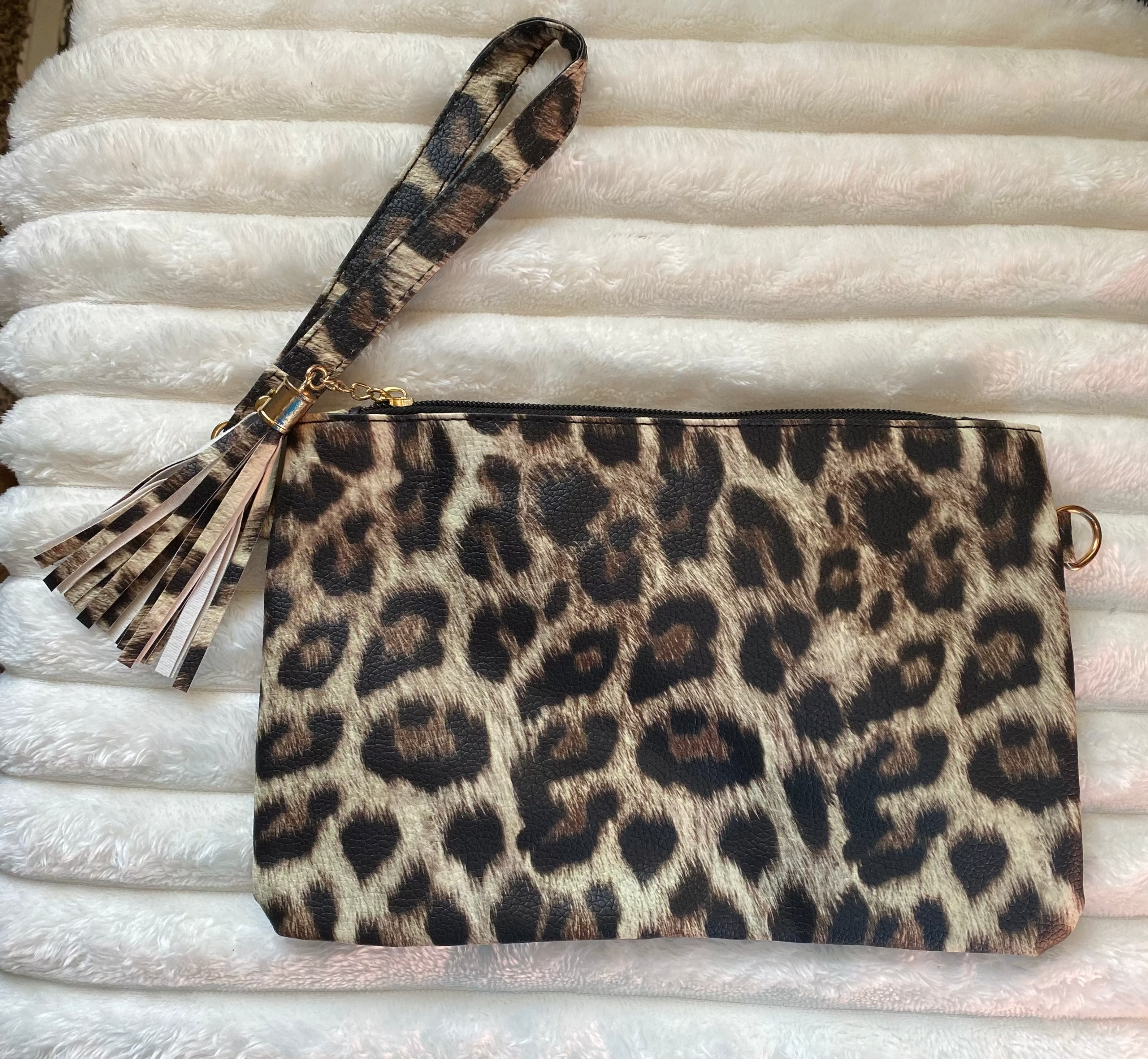 Leopard print clutch with matching wristlet on a textured white surface