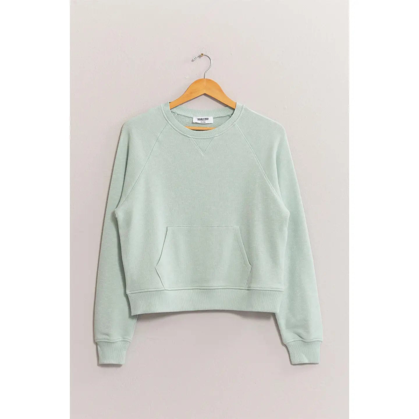 Light green sweatshirt on a wooden hanger against a plain background