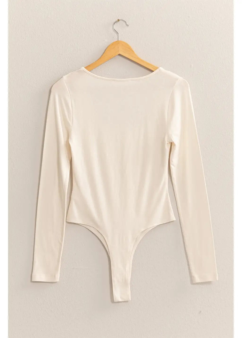 Beige bodysuit on a hanger against a plain background